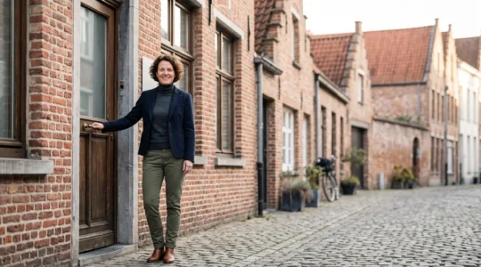 Dirigeant de PME belge devant une façade de bureau en briques, symbolisant l'équilibre entre conformité sociale et croissance